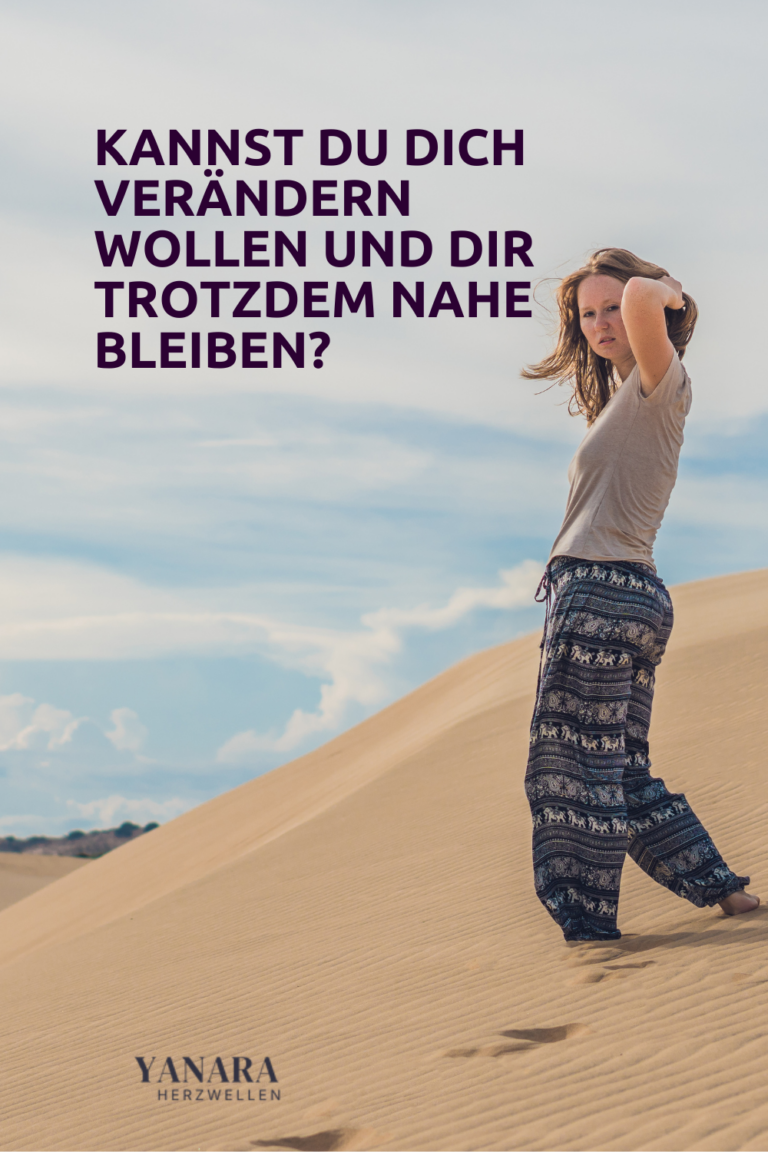 Frau geht barfuß durch eine weite Dünenlandschaft und blickt zurück.